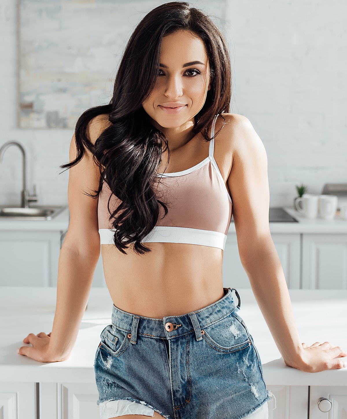 Woman in casual outfit smiling in kitchen.